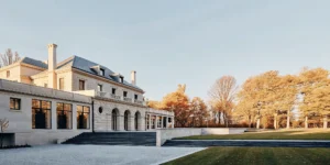 Exterior of a grand French Chateau-inspired private estate in Dedham Massachusetts with manicured lawns and autumn foliage