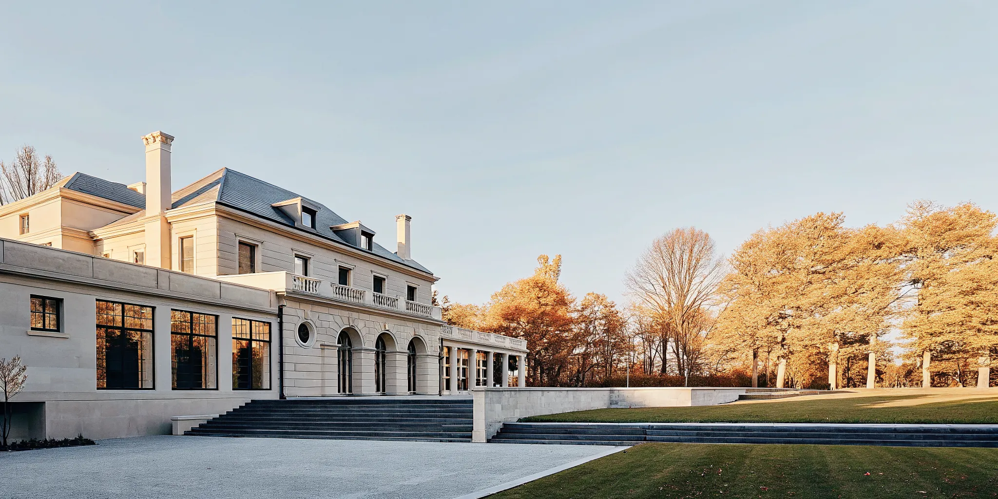 Exterior of a grand French Chateau-inspired private estate in Dedham Massachusetts with manicured lawns and autumn foliage