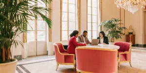 Leadership team gathered around a conference table in an elegant estate setting with French chateau architecture and natural light